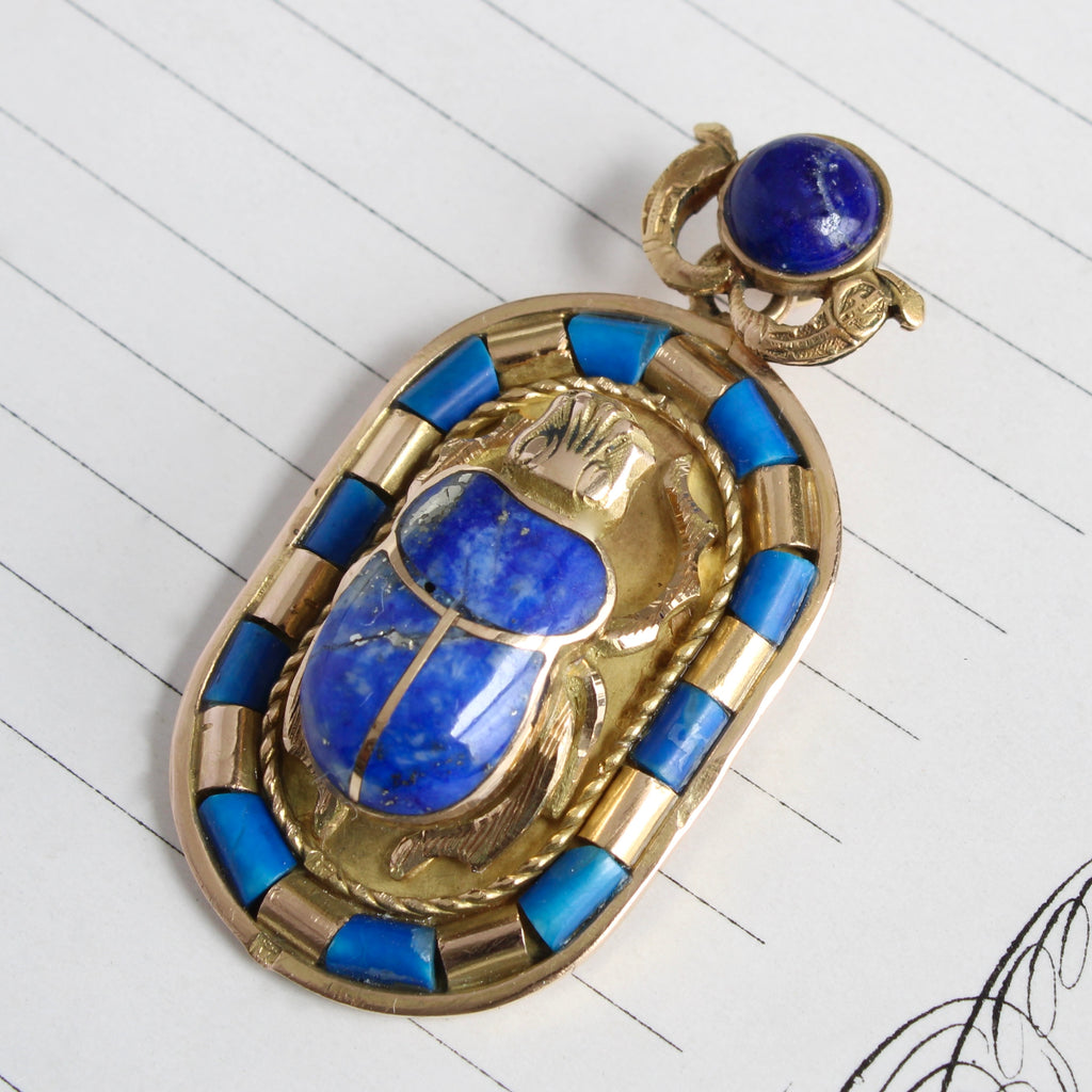 gold pendant with a scarab inlaid with lapis lazuli and a frame of gold and lapis tube beads