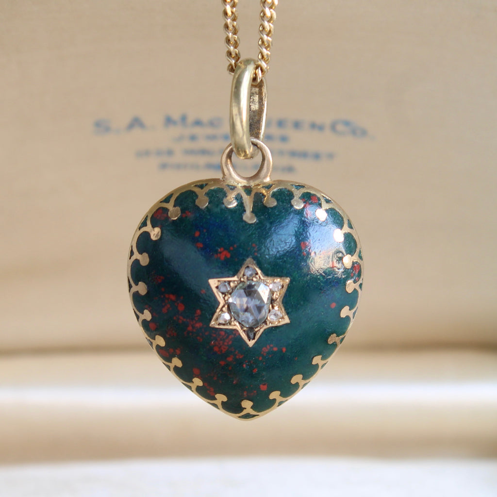 heart shaped locket in gold with the front cover made from a green stone with red dots, a six pointed star in the center set with diamonds, on a gold chain