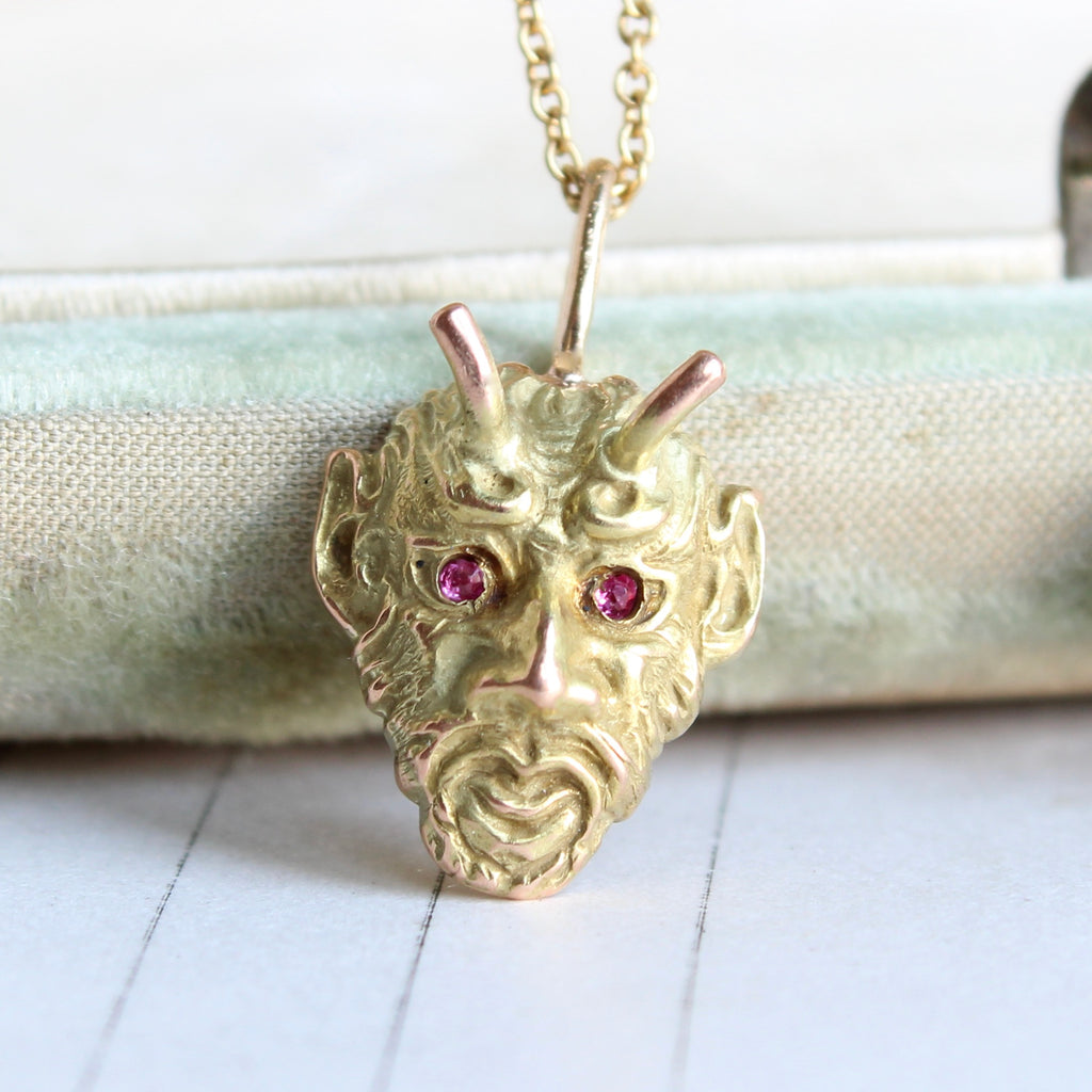 yellow gold devil face charm with ruby eyes on a gold chain