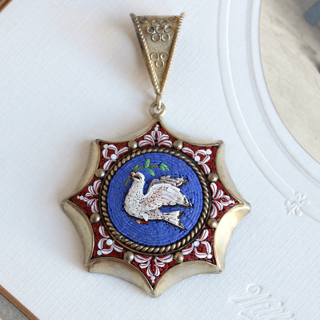 micro mosaic dove against a royal blue backround set in the cover of a silver locket