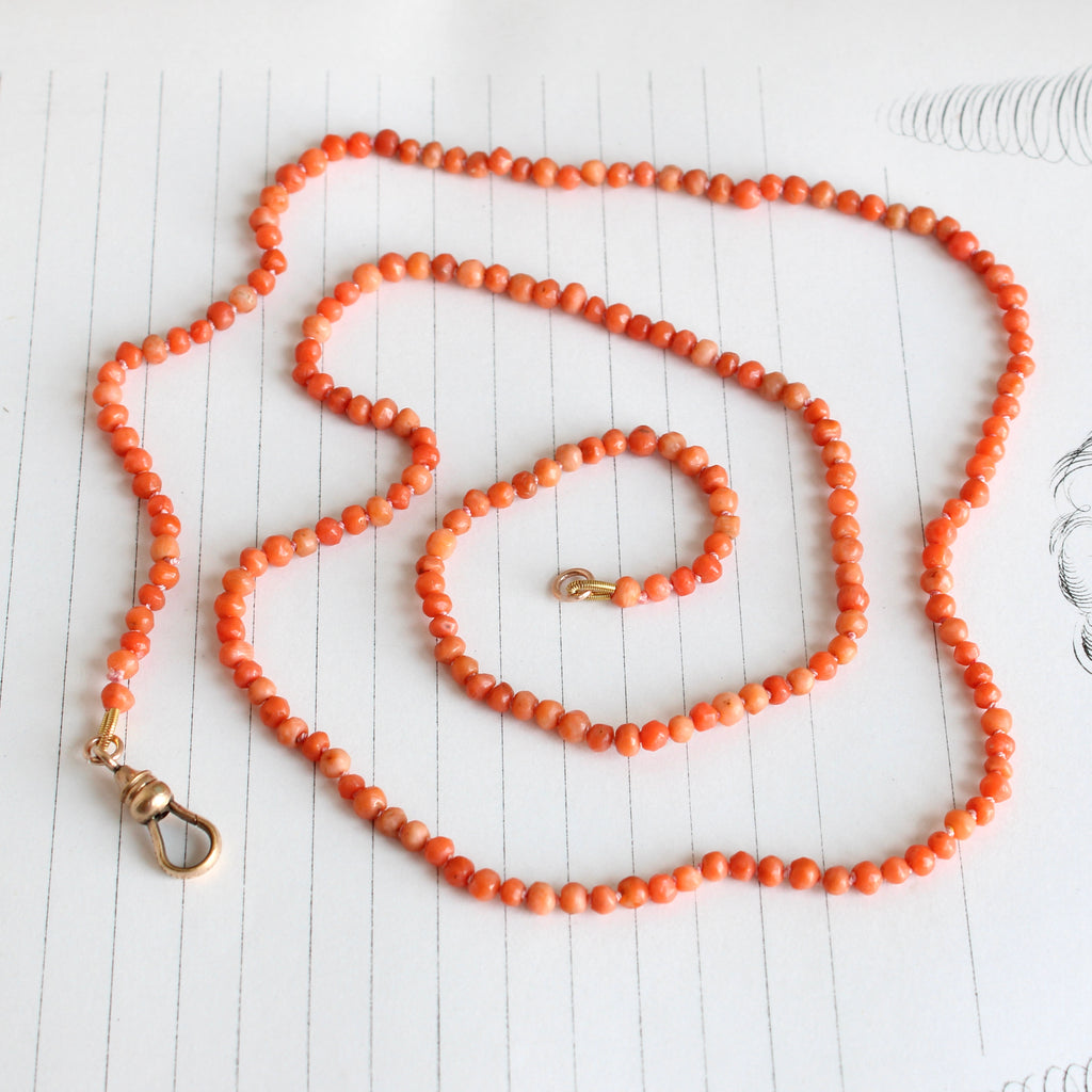 small salmon colored coral beads knotted on pink silk with a clip clasp