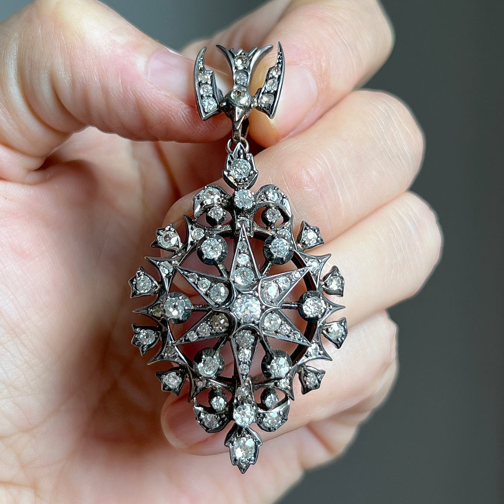 silver pendant with a dove decorating the bail at the top and a star shaped drop completely studded with diamonds