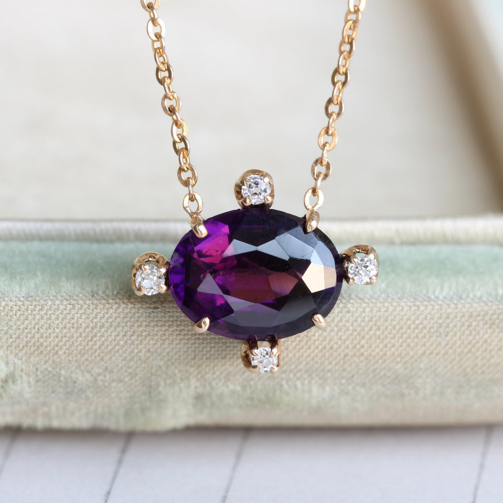 deep purple gem with four bright diamond accents on a gold chain