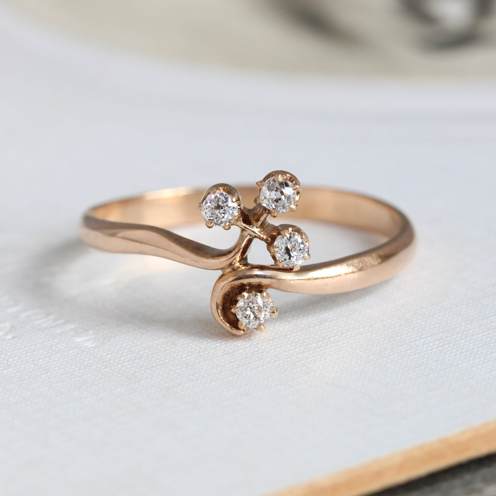 a yellow gold ring with four very bright old cut diamonds set in a clover motif