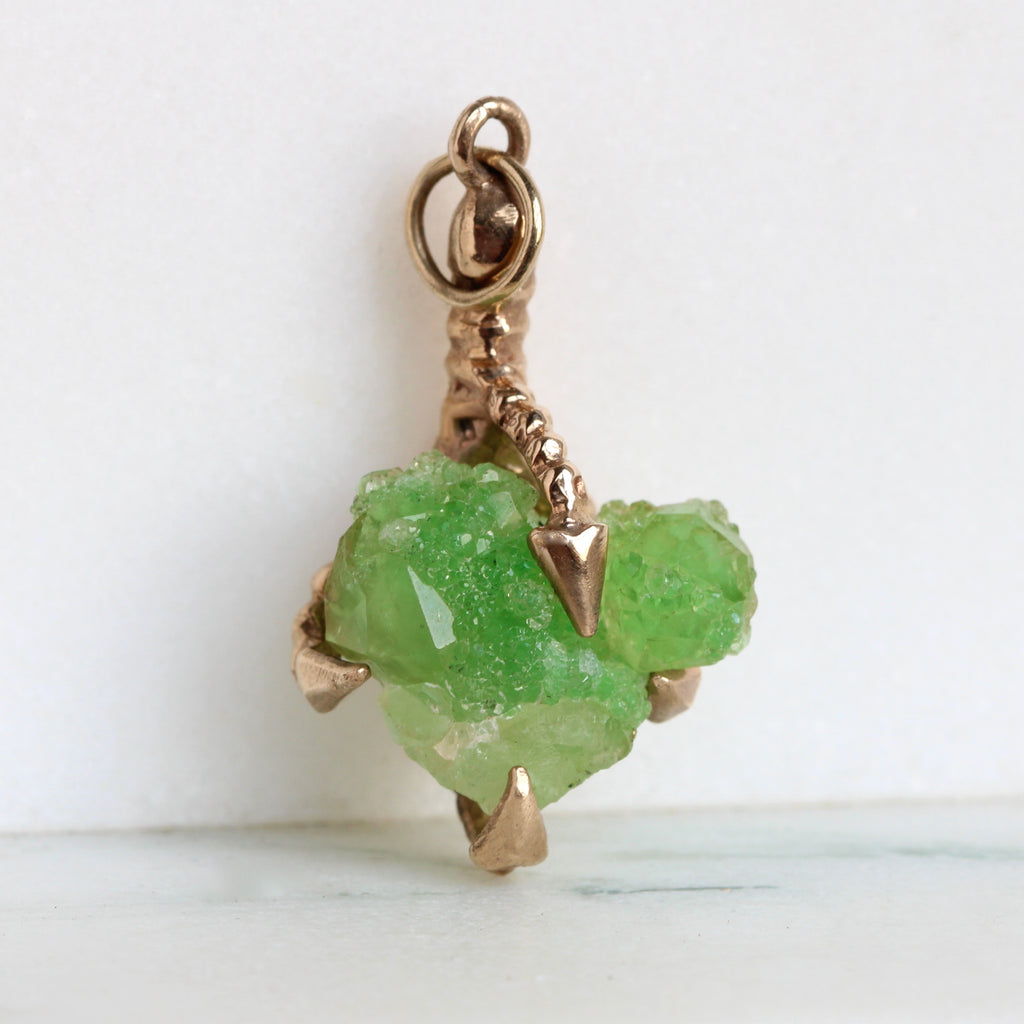 heart shaped rough green garnet crystal held in yellow gold claw pendant