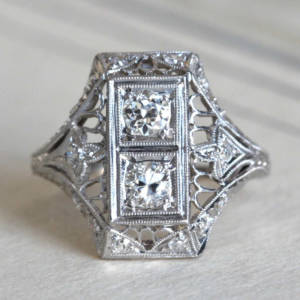  platinum filigree ring with a recentagular face set with two sparkly round diamonds and smaller diamonds on the sides