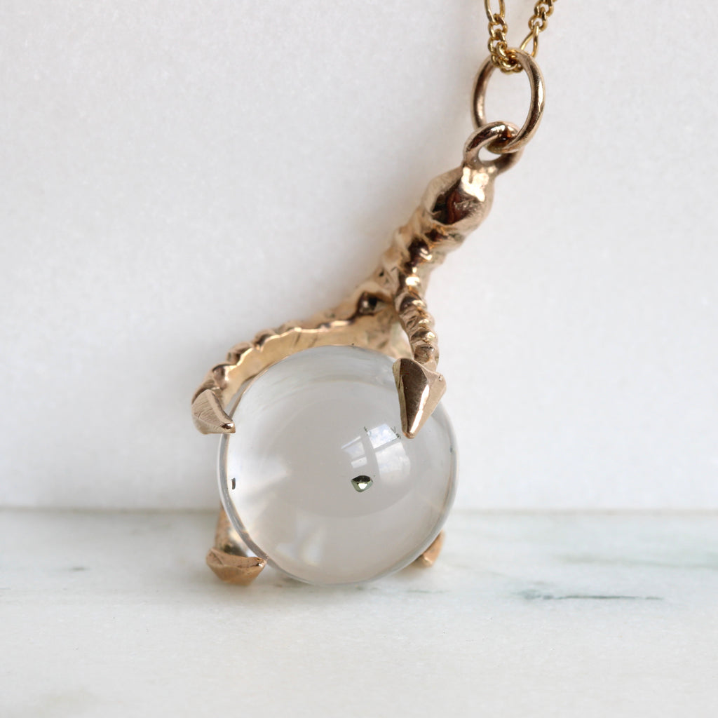 tiny pyrite cube suspended in rock crystal ball set as a pendant in a yellow gold claw