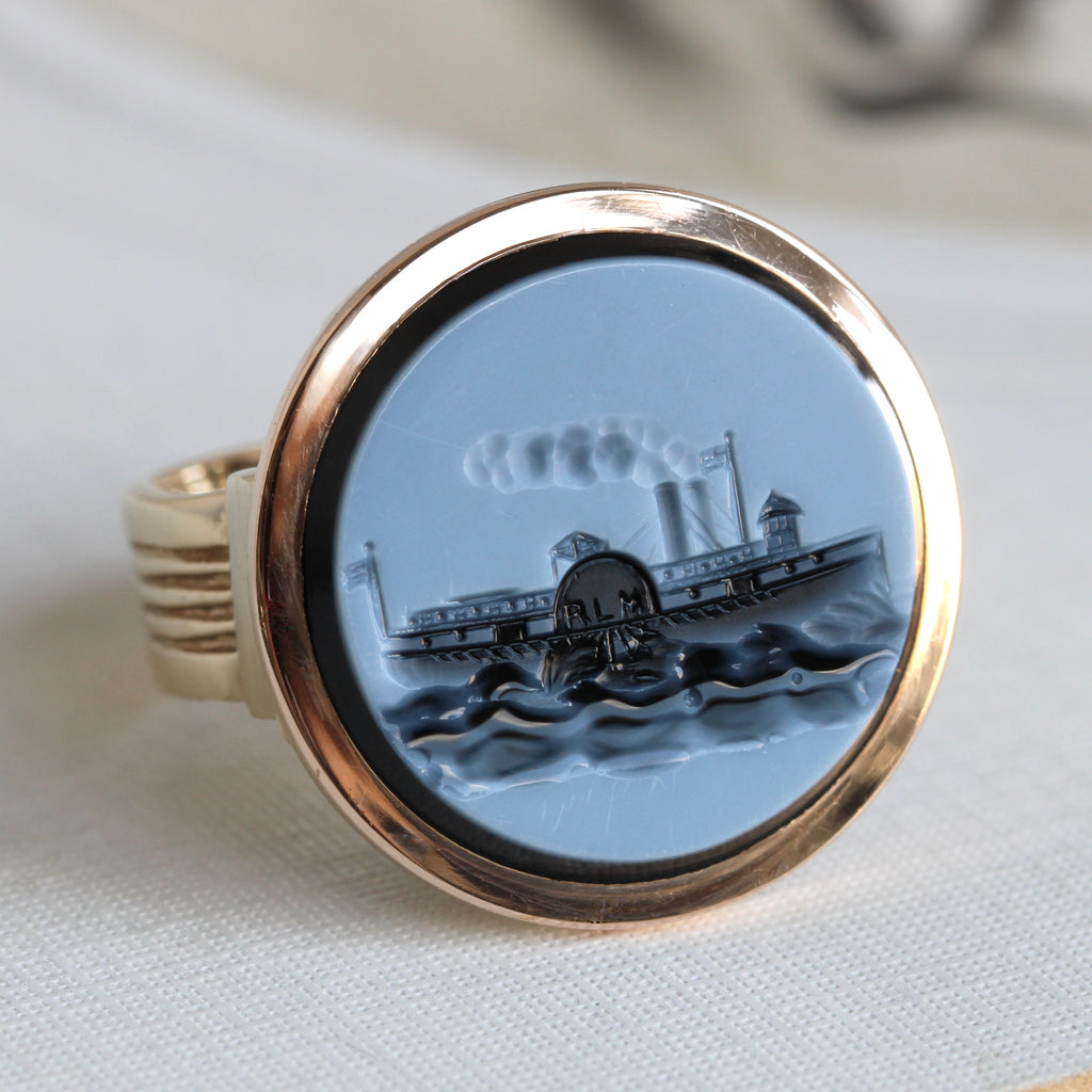 round carving of a paddle steam boat in black and white onyx set in a gold ring