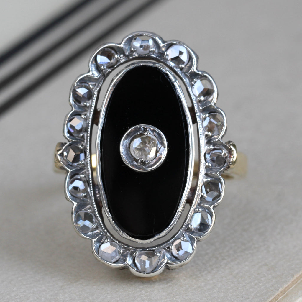 Antique yellow gold ring with an oval black onyx face surrounded by rose cut diamonds set in silver and single rose-cut diamond in the center of onyx