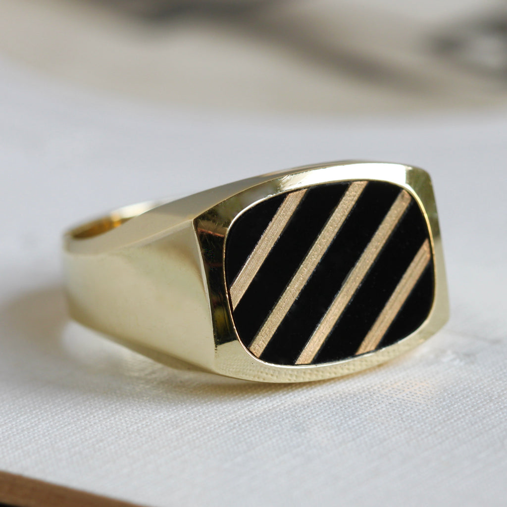 yellow gold ring with rectangular face that has a black onyx inset with gold stripes