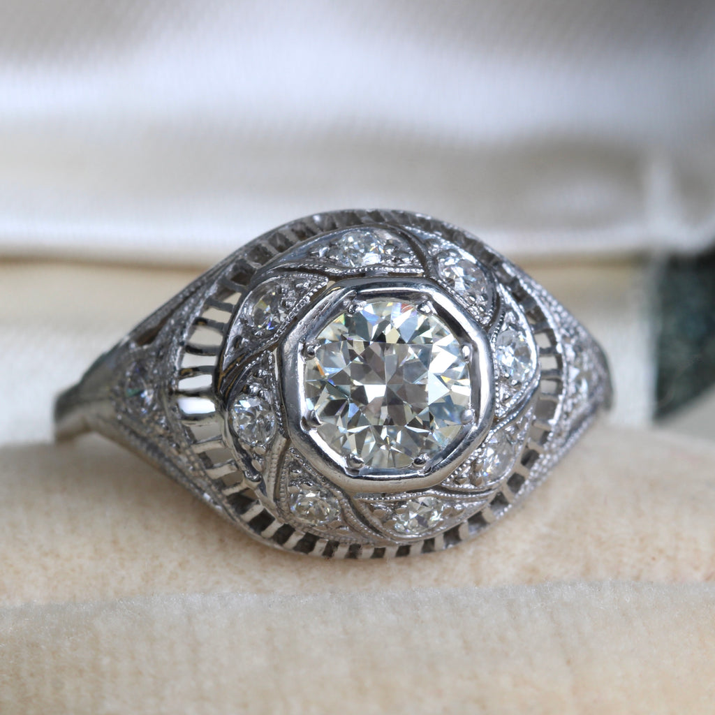 white gold ring in a filigree dome style with a large old cut diamond in the center and smaller mine cut diamond accents around it