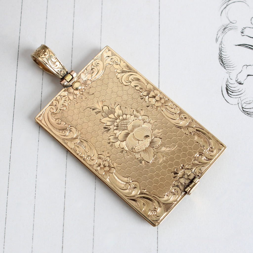 yellow gold notebook pendant with pages made from bone inside that can be written on then wiped clean 