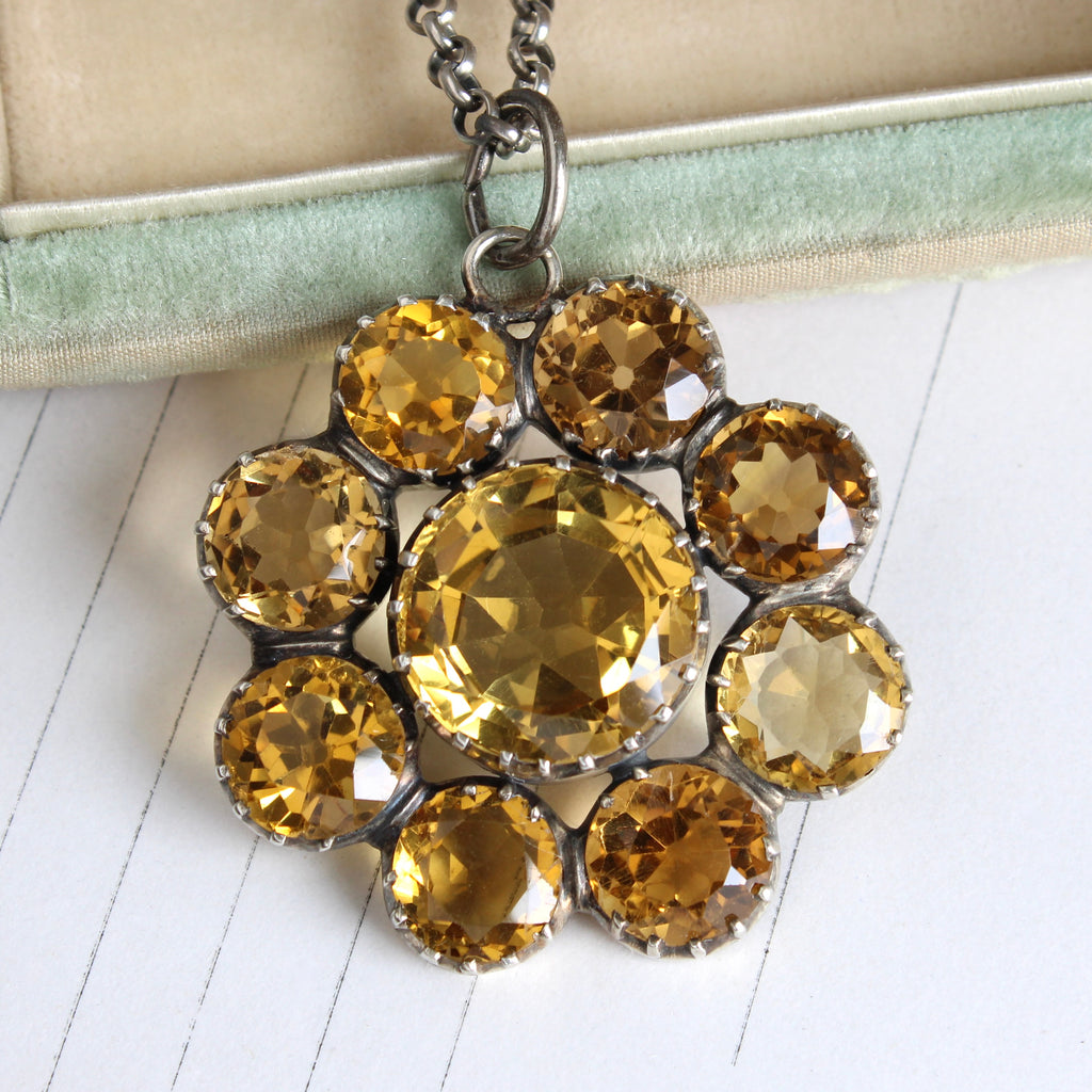 deep golden round citrine set in a halo cluster as a pendant in silver on a silver chain