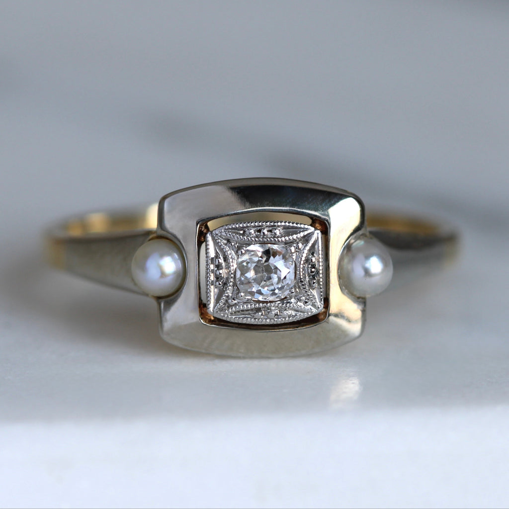 Gold ring with a diamond and pearls on eather side in silver and gold metal