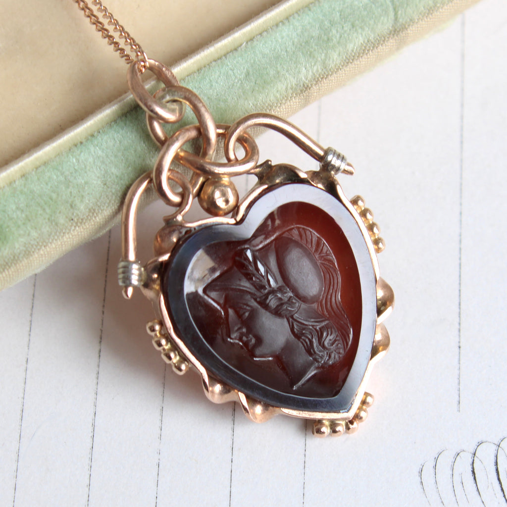 heart shaped cameo carving of the  greek goddess athena set in a rose gold and platinum bezel with scrolled top on a chain