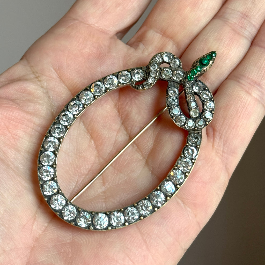 brooch designed as a coiled snake set with bright rhinestones and emerald green stones in the head