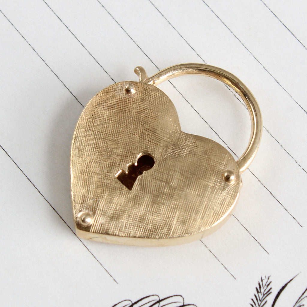 large yellow gold heart shaped padlock with key hole and a crosshatched texture finish.
