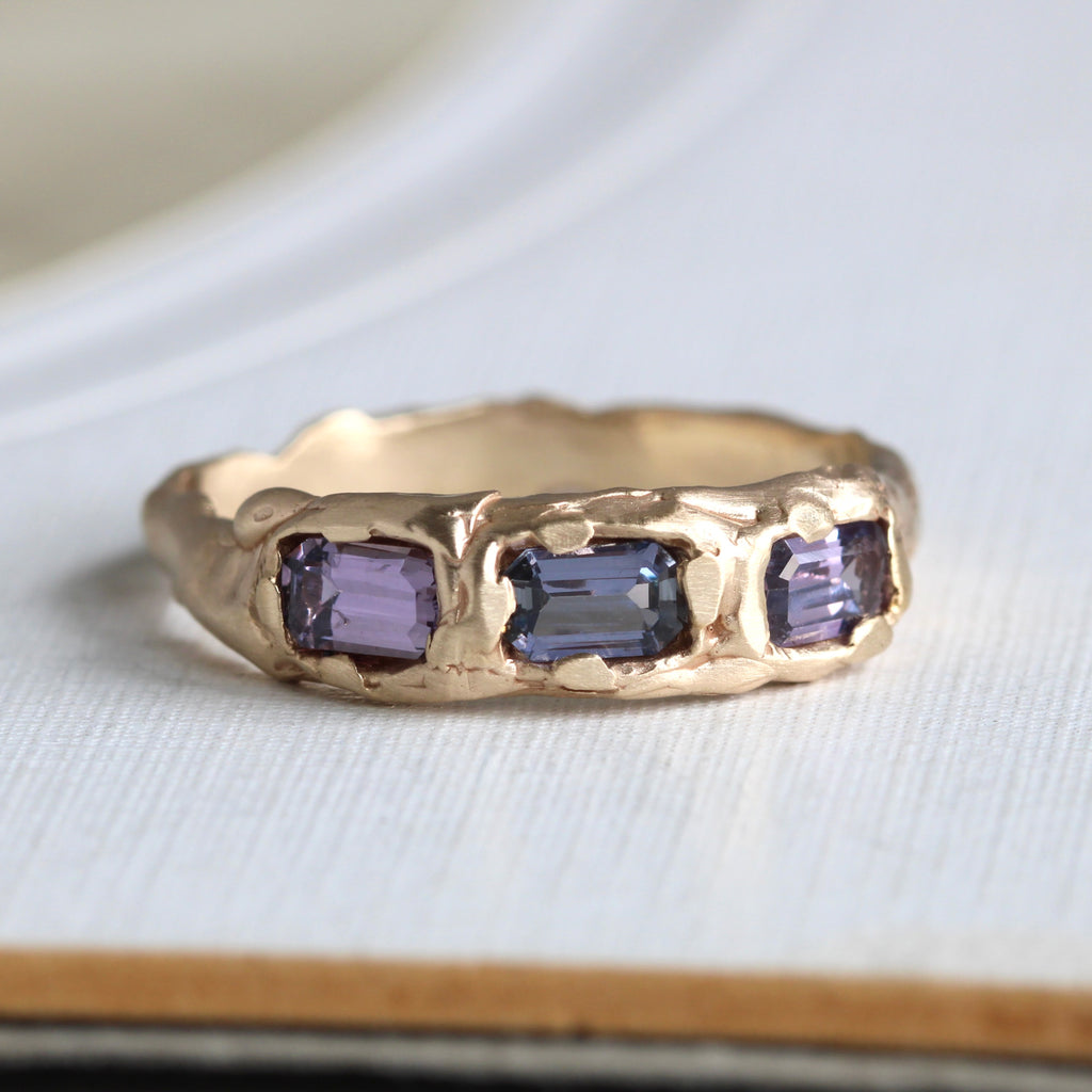 yellow gold ring in hammered organic branch style with three sapphire baguettes set across the front in slightly differing shades of purple