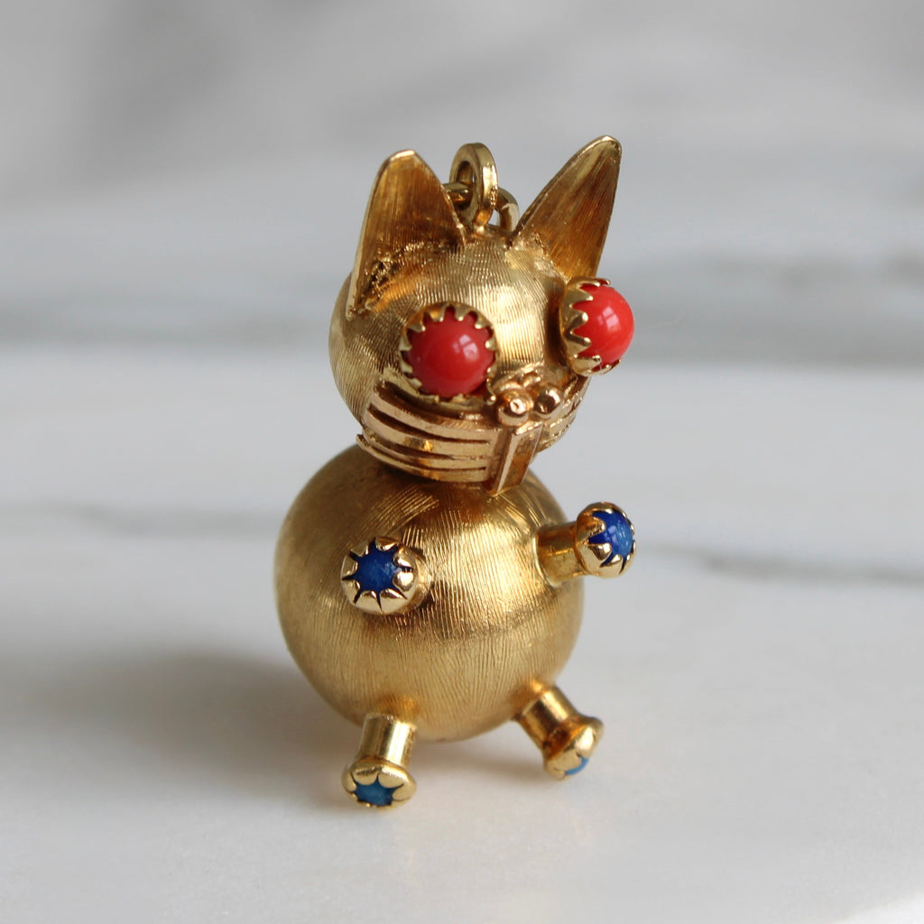 cat charm in yellow gold with the body made of two balls and coral eyes