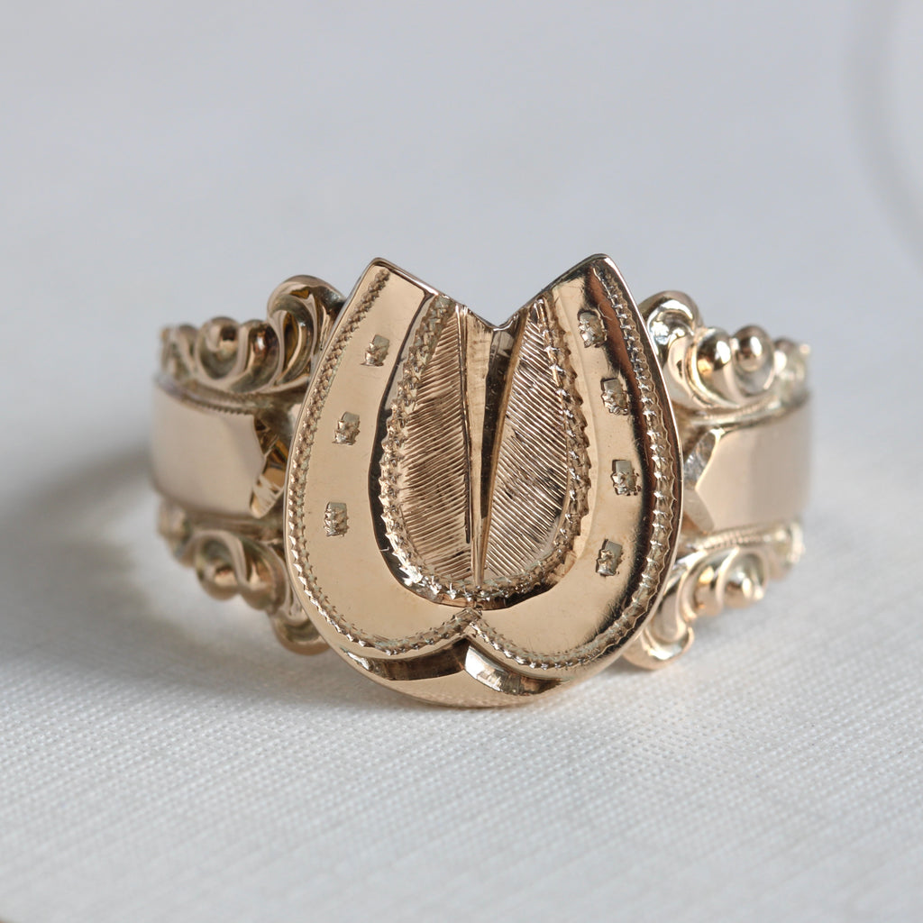 ring of slightly rosy yellow gold with a horseshoe design as the center and scrolled shoulders