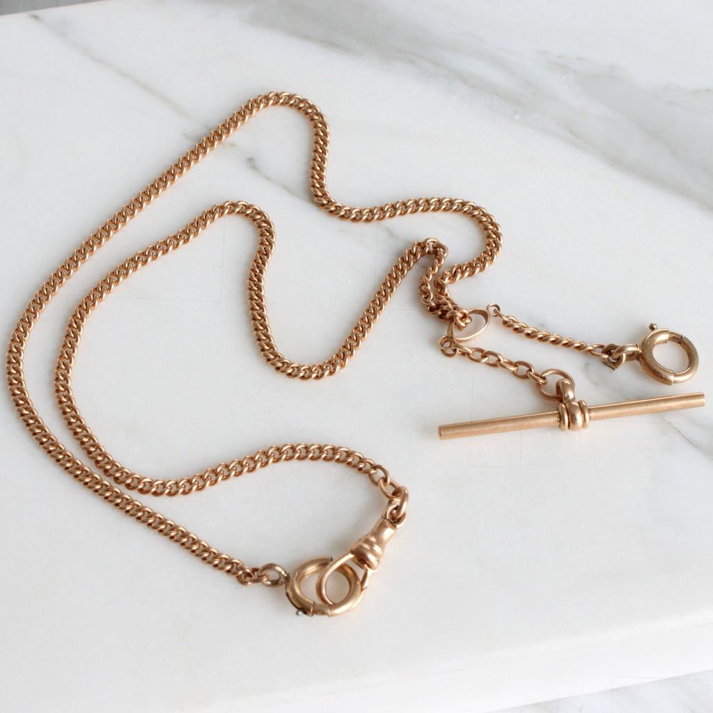 a gold chain with different style clasps that can hold pendants and a gold bar drop 