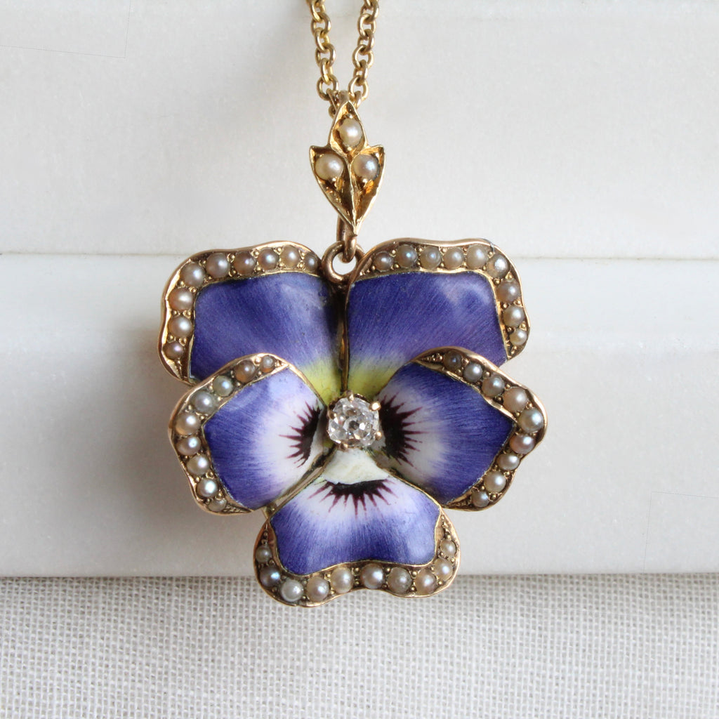 yellow gold flower pendant enameled like a purple pansy set with a diamond in the center and pearls edging each petal, on a gold chain