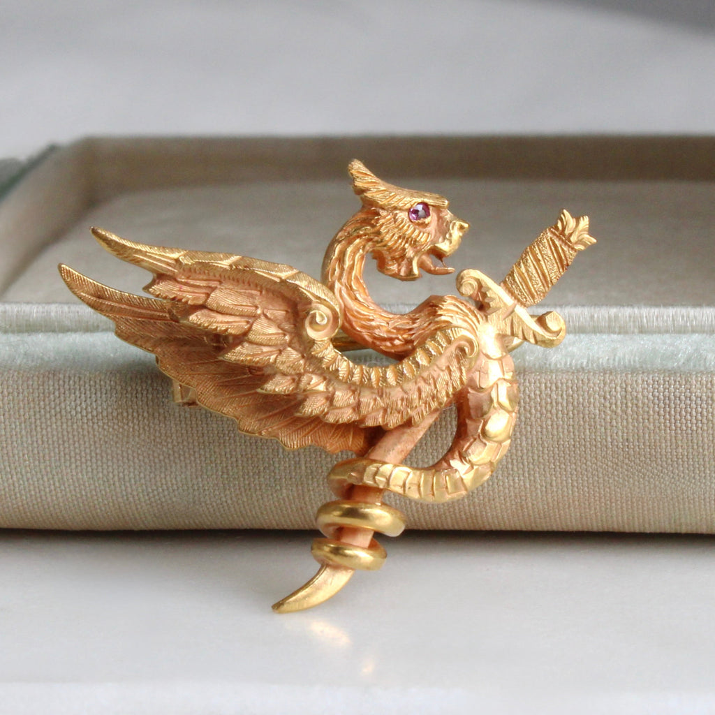 yellow gold brooch designed as a dragon curled around a sword.