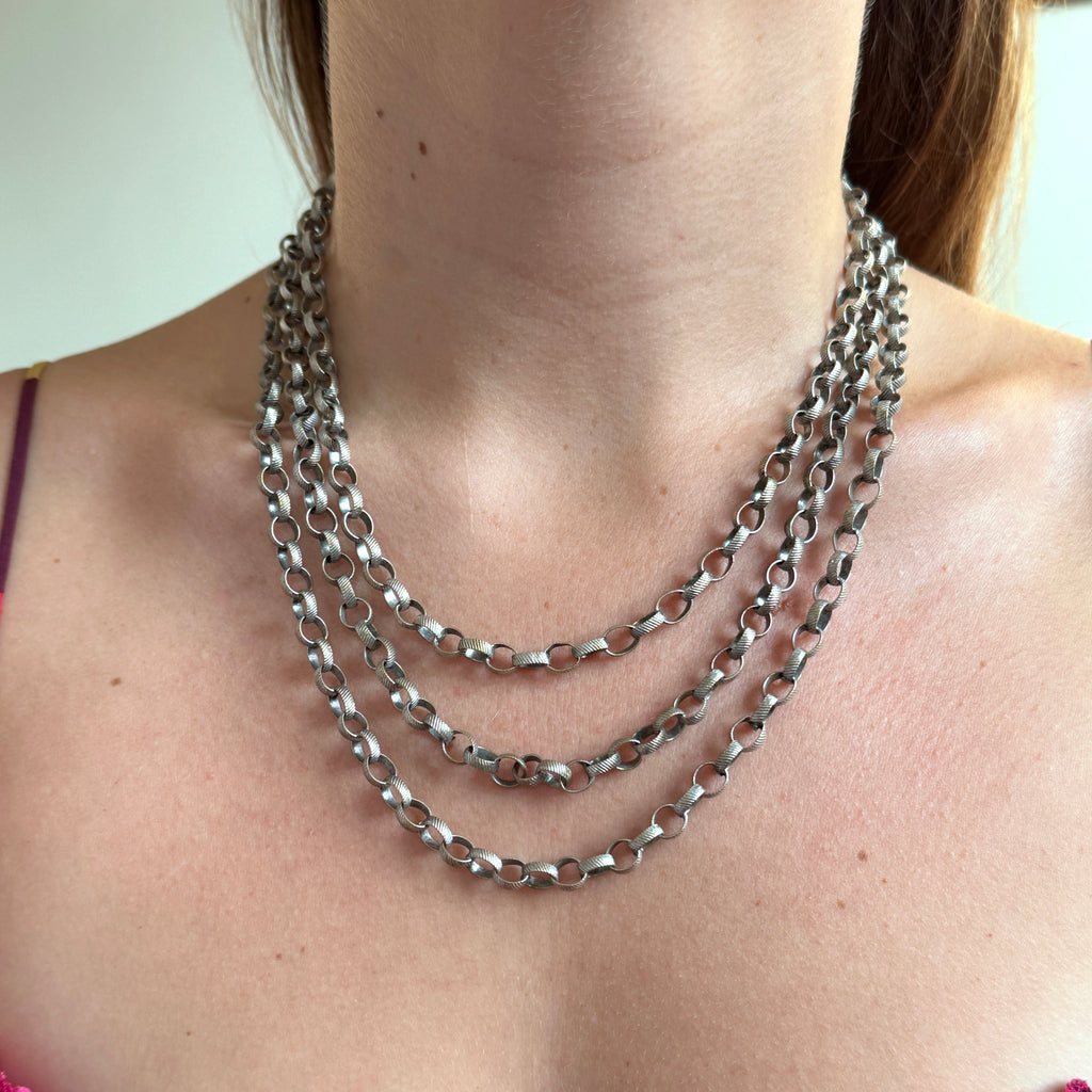 very long round link chain in silver with a ribbed pattern on each link