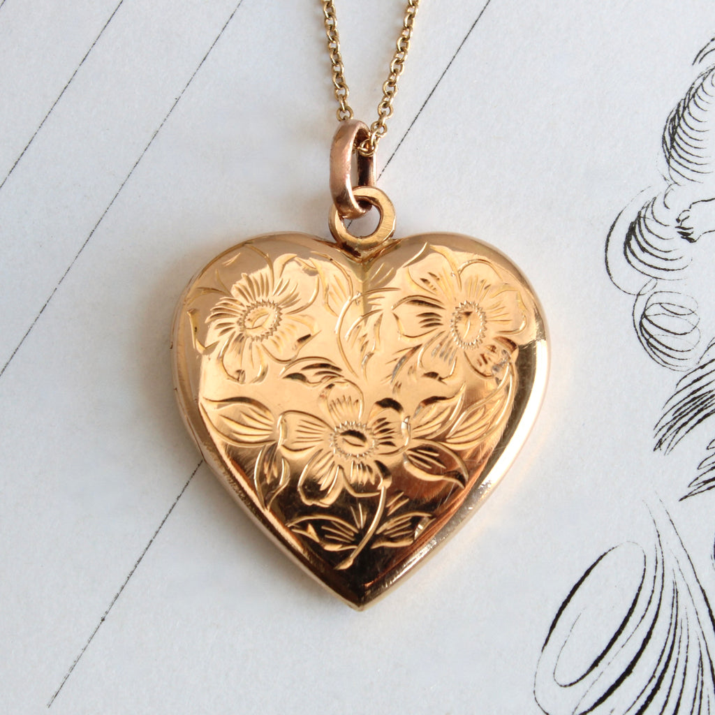 gold heart shaped locket with flowers engraved on the front, on a gold chain