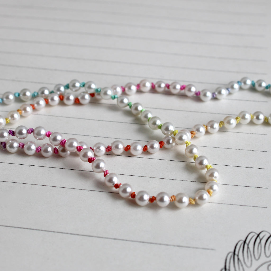 very small cultured pearls knotted on rainbow ombre silk with a god clasp
