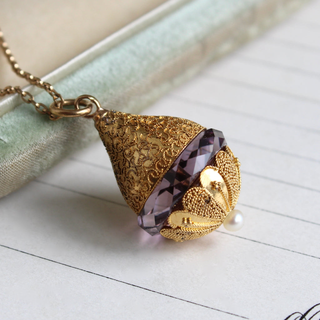 teradrop shaped gold pendant with a slice of amethyst in the center and a pearl accents at the bottom, on a gold chain
