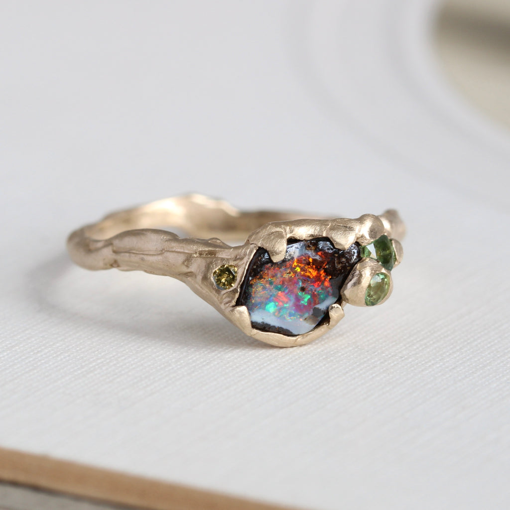 yellow gold ring with boulder opal that has bright flashes of red yellow and turquoise in a branch style mounting
