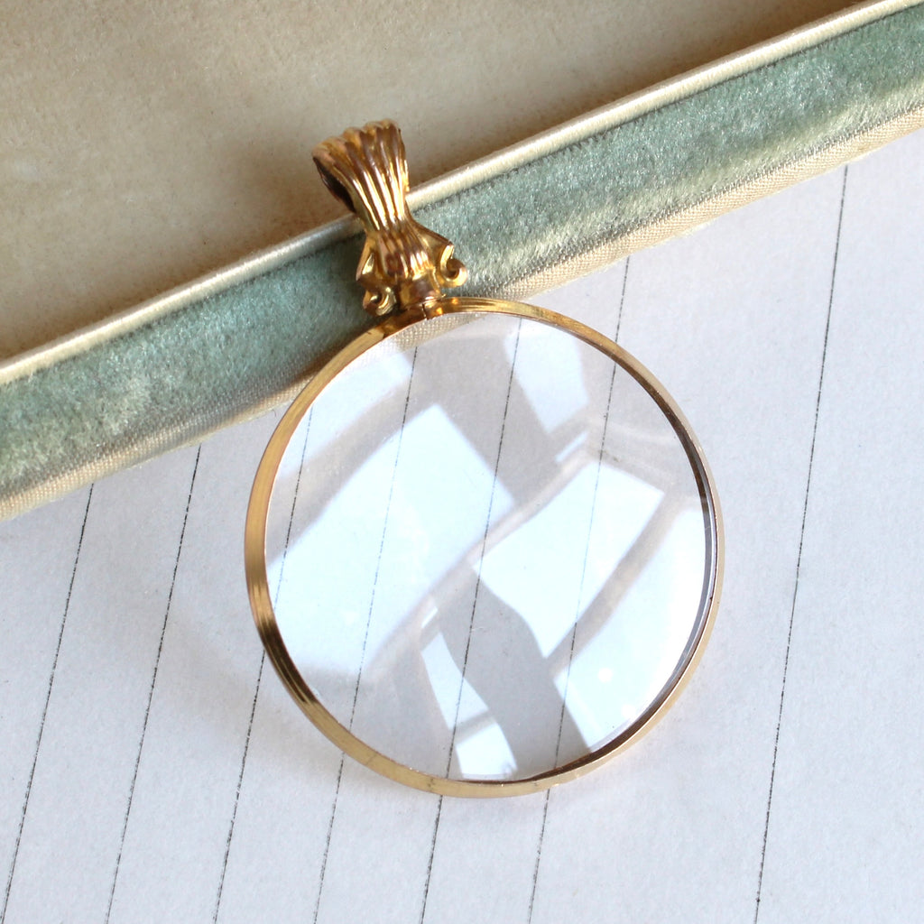 locket with gold frame and glass on both sides so object within can be seen front and back