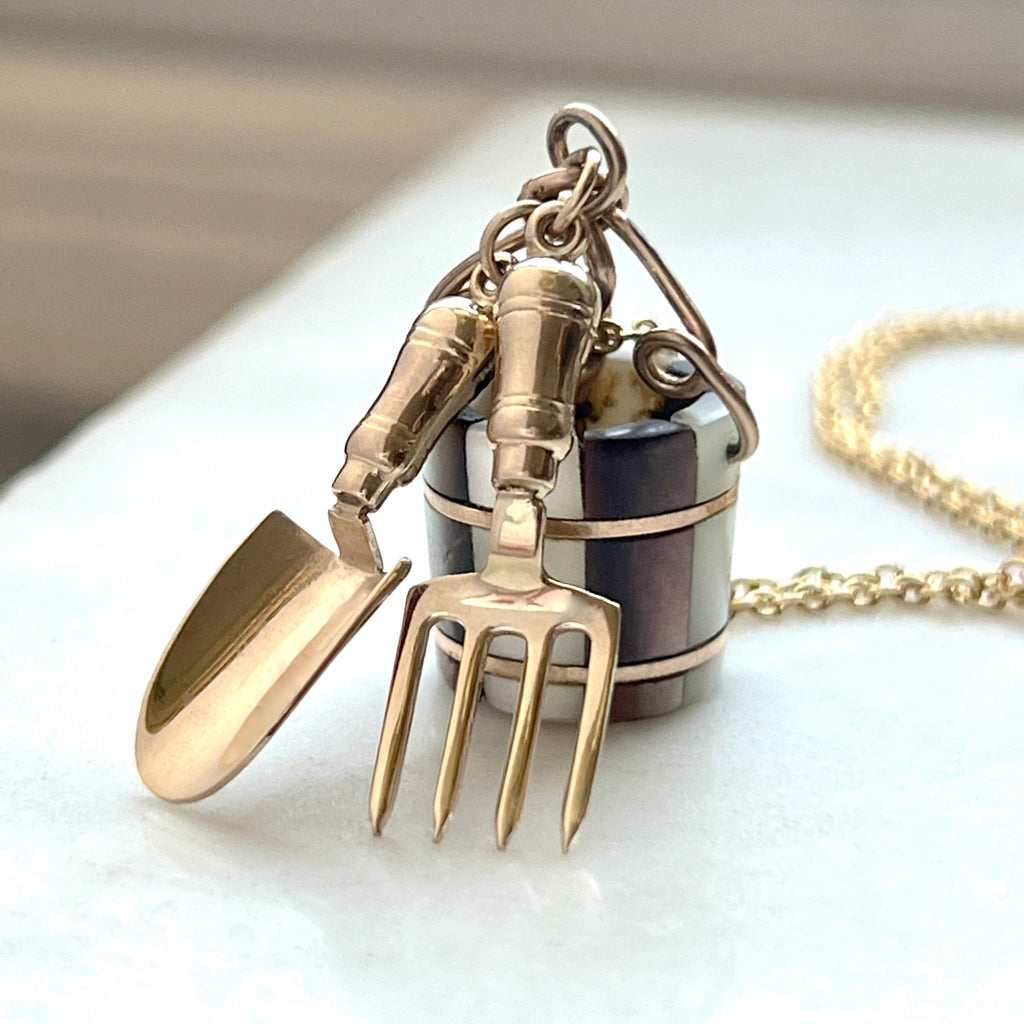 charm necklace with miniature garden tools in gold with a tiny mother of pearl bucket charm
