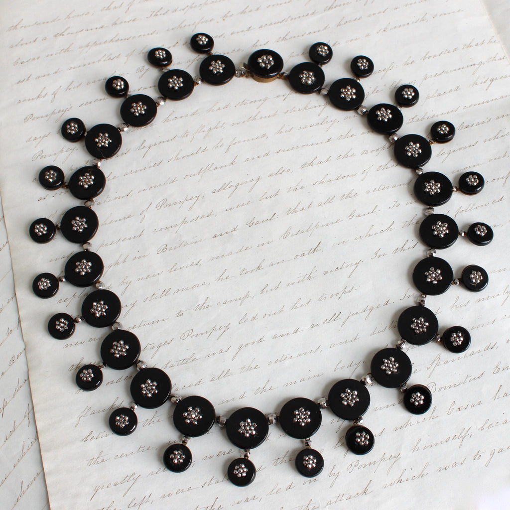 antique collar style necklace of joined black glass discs each with a cut steel flower in the center 
