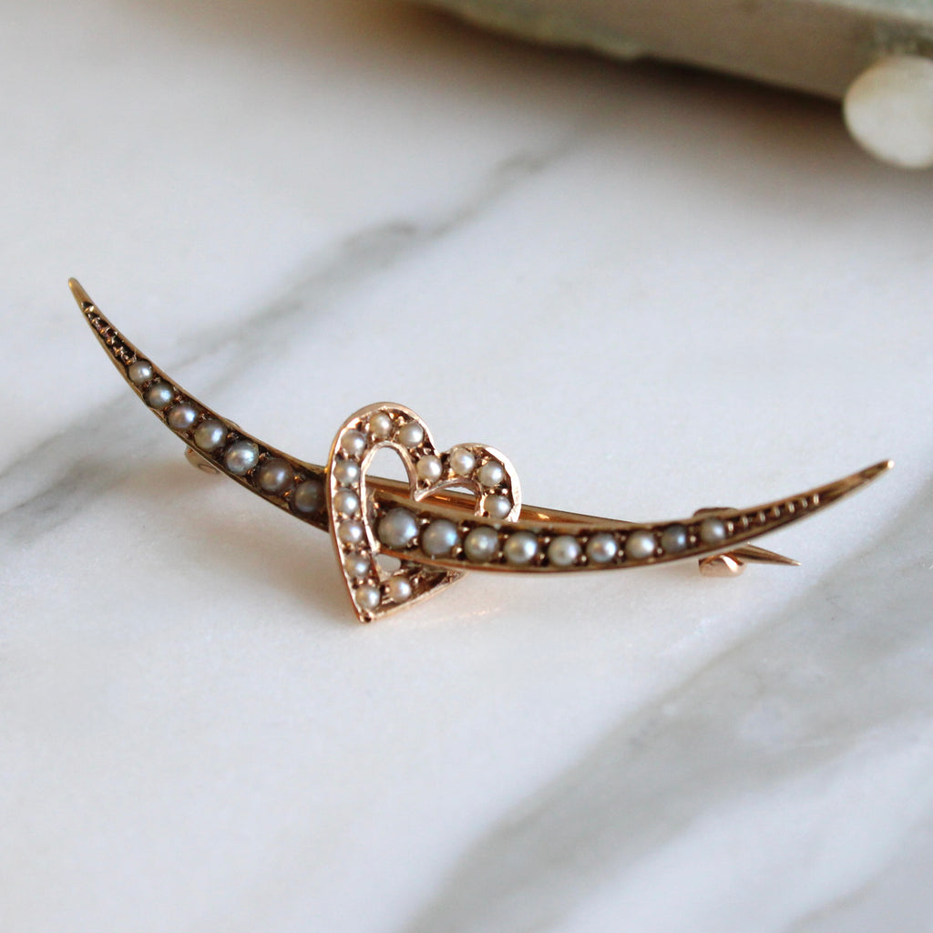 gold brooch in a curved crescent shape with a heart all set in seed pearls