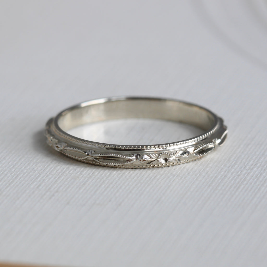 white gold ring with orange blossom and ribbon design all around the band.