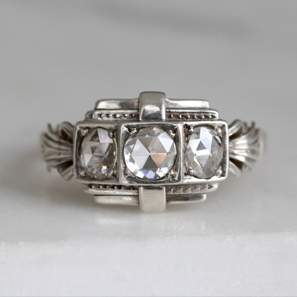 Silver and gold ring with three diamonds across the front, the diamonds cut with small triangular facets