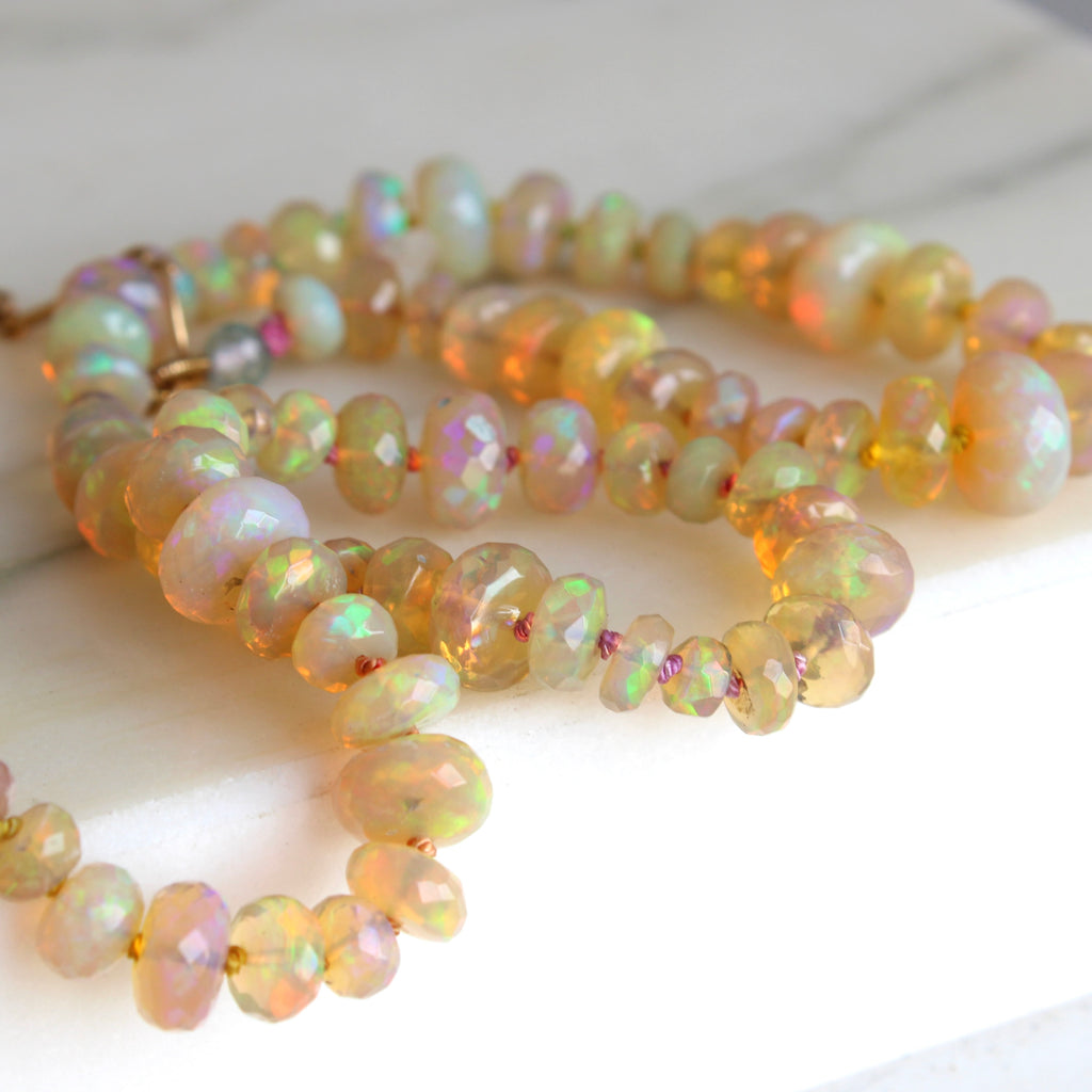 faceted opal beads knotted on pastel rainbow silk with a heart charm at the clasp end