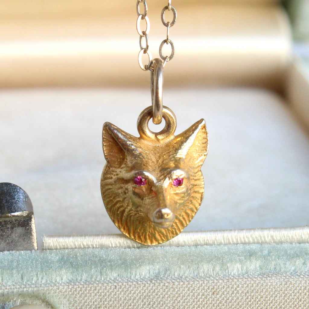 small yellow gold fox face charm with ruby eyes on a gold chain