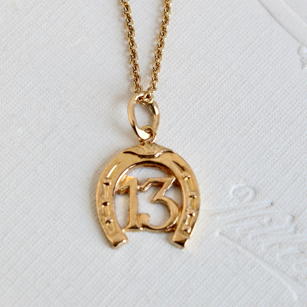 tiny gold #13 in a horseshoe charm on a chain