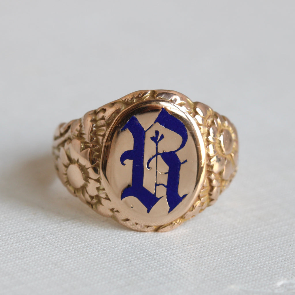 gold signet ring with flowers on the shoulder and an initial r enameled in cobalt blue