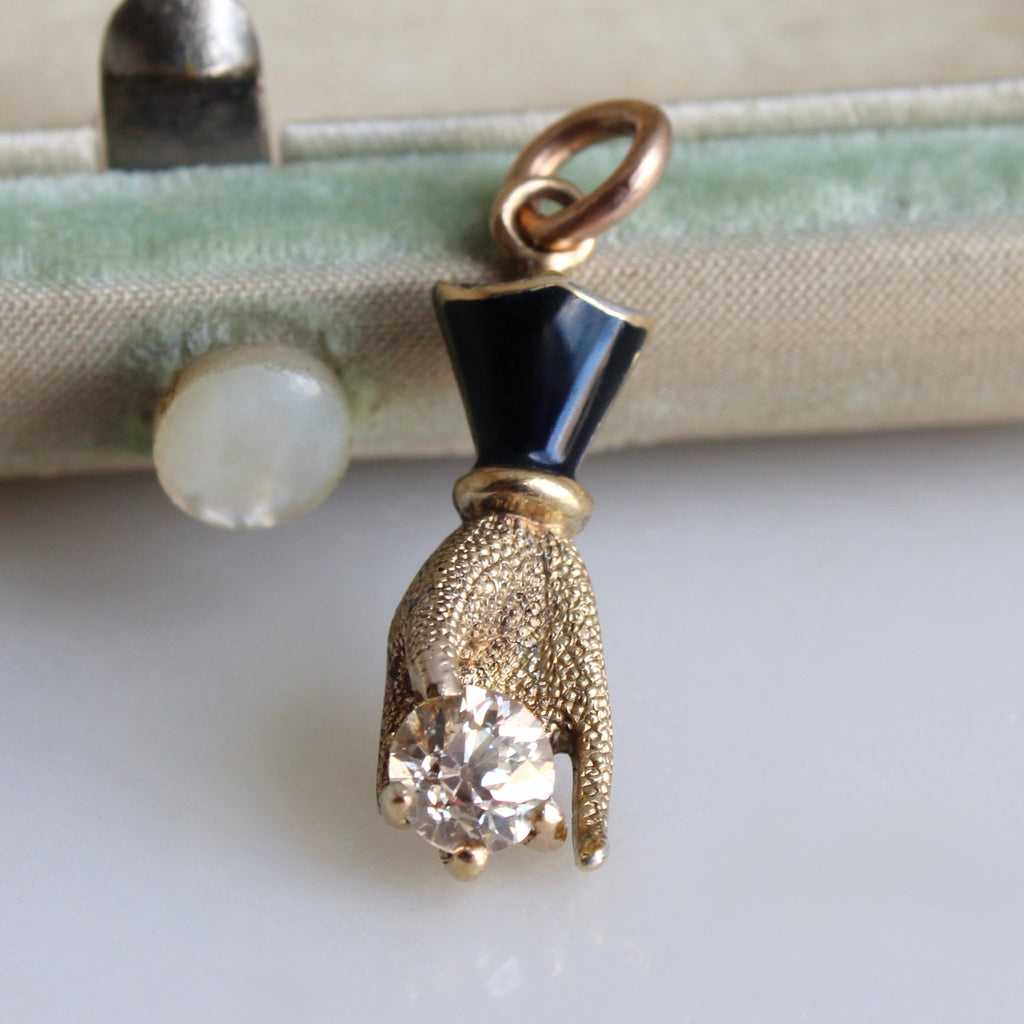 a gold hand pendant holding a natural champagne tinged diamond