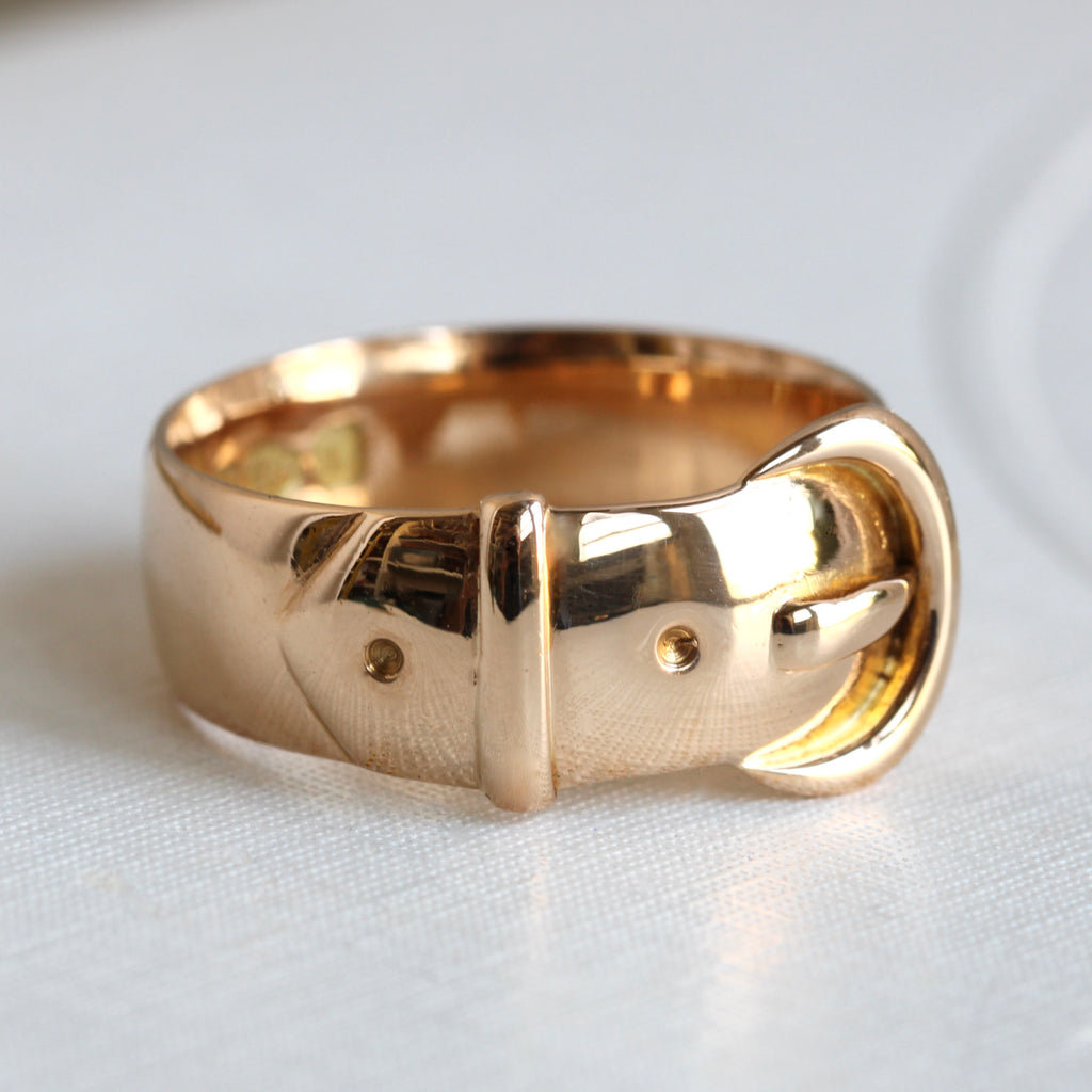 yellow gold ring designed to look like a clasped belt with a large rounded buckle