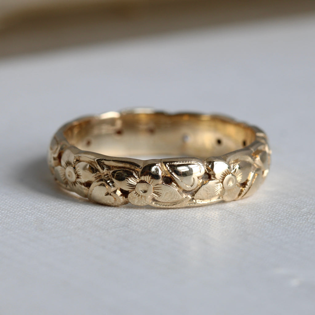 yellow gold band with a design of orange blossom and ivy leaves carved all around the outside
