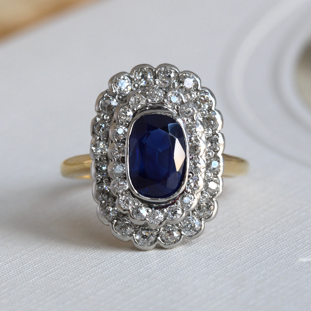 antique ring with deep blue oval sapphire surrounded by a platinum double halo frame set with old mine cut diamonds, yellow gold shank