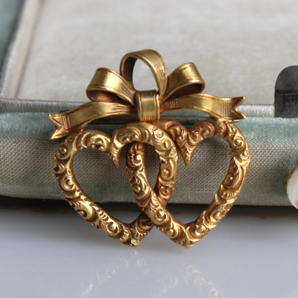 brooch of two gold linked hearts with a bow on top