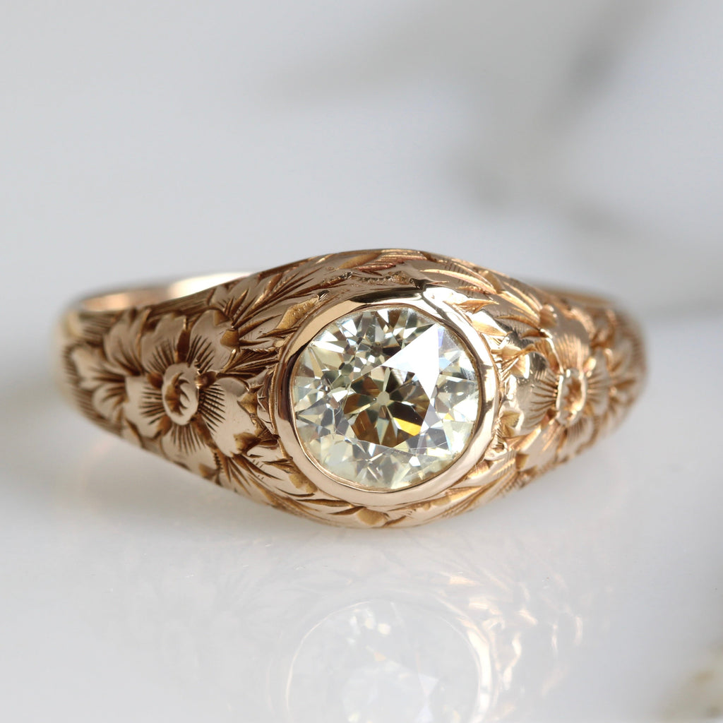 Gold ring with floral engraving and a diamond in a smooth bezel mounting 
