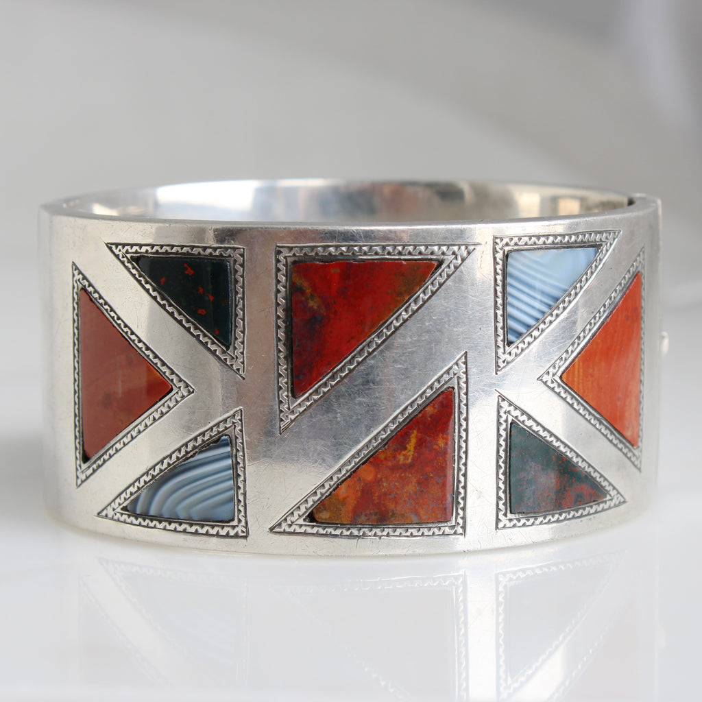 wide silver bangle set with triangles of red, green and gray striped stones