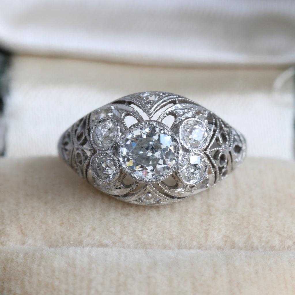 lacey filigree dome ring in platinum set with one old cut diamond in the center, the sides dotted with additional diamonds